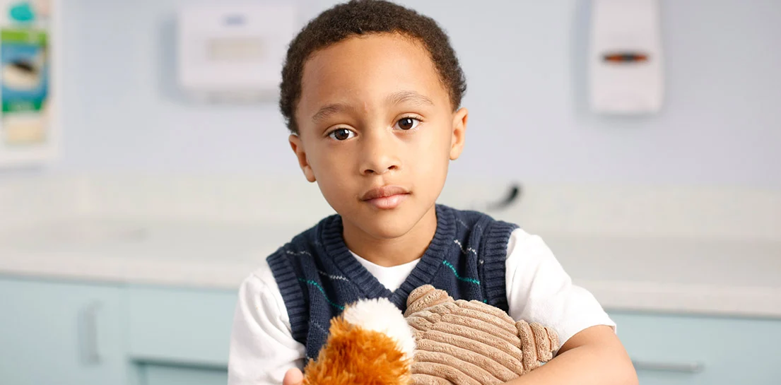 Image of young boy in vest holding stuffed animal 